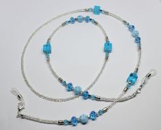 "A lovely glasses chain made using blue tones crystal and glass beads. The glasses chain measures approximately 28\" in length and is finished with rubber ends to securely attach your reading glasses or sunglasses.  Very striking and beautiful chain. Lovely gift idea. Wrapped in tissue paper and presented in an organza pouch." Blue Beaded Chain Glasses Chains With Round Beads, Blue Glass Necklaces With Adjustable Chain, Blue Beaded Glasses Chains, Blue Glasses Chains With Round Beaded Chain, Elegant Adjustable Blue Glasses Chains, Elegant Blue Adjustable Glasses Chains, Handmade Blue Glass Glasses Chains, Blue Glass Beaded Chain Jewelry, Adjustable Blue Beaded Necklaces