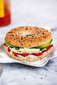 a bagel sandwich with cheese, lettuce and tomatoes