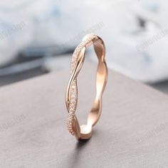 a gold wedding band with white diamonds on the inside and outside, sitting on top of a table