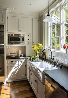 a large kitchen with white cabinets and stainless steel appliances in the center, along with wooden floors