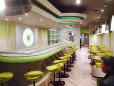 the interior of a restaurant with yellow chairs and green counter tops, along with neon lights