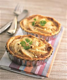 two small pies sitting on top of a table next to a fork and knife