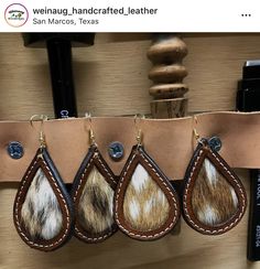 three pairs of leather earrings hanging from a hook