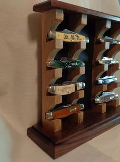 a wooden wine rack with several bottles and knives on it's sides, attached to the wall