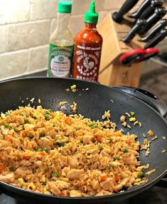 chicken and rice in a skillet next to bottles of hot sauce