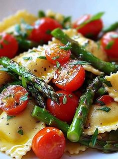 pasta with asparagus, tomatoes and parmesan cheese on a white plate