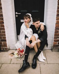 a man and woman sitting on the ground next to each other in front of a door