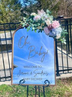 a blue sign with flowers on it that says oh baby welcome to james & sonder's baby shower