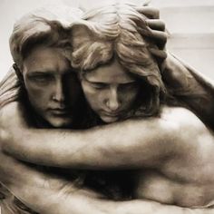 a statue of two people hugging each other with their arms around one another's shoulders