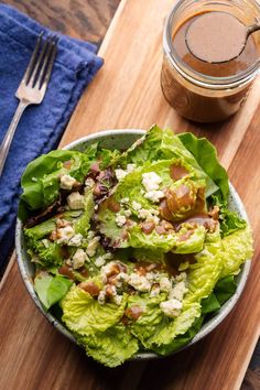 a salad with lettuce and nuts in a bowl next to a cup of coffee