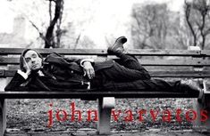 a man laying on top of a wooden bench next to a park filled with trees