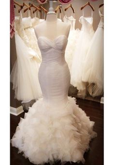 a white wedding dress is on display in a bridal room with other gowns