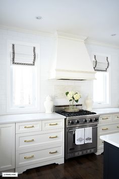 a stove top oven sitting inside of a kitchen next to white cabinets and counter tops