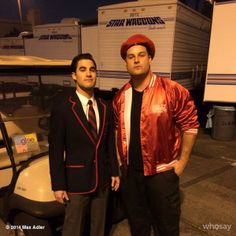 two men standing next to each other in front of a trailer