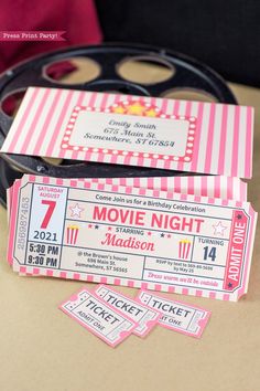 two pink and white movie tickets sitting on top of a table