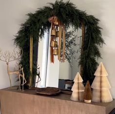 a christmas wreath on top of a mantle next to a mirror and other items in front of it