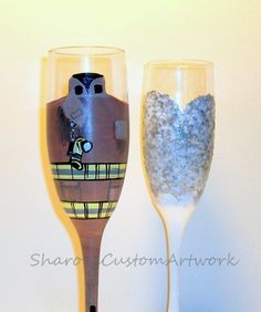 two wine glasses with designs on them sitting next to each other in front of a white wall