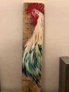 a painting of a rooster sitting on top of a wooden block in front of a white wall