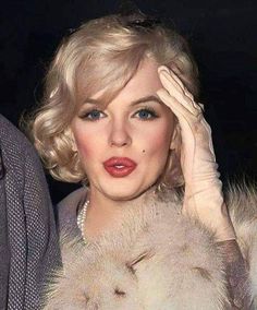 a woman with blonde hair and blue eyes is wearing a fur stole around her neck