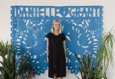 a woman standing in front of a blue wall with an intricate cut out design on it