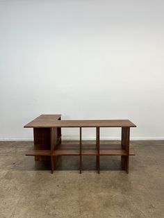 a wooden table sitting on top of a cement floor next to a white wall in an empty room