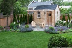 a small wooden shed sitting in the middle of a lush green yard