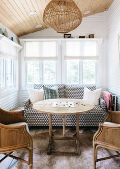 a living room with couches, chairs and a round table in front of two windows