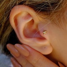 a close up of a person's ear with a small gold star on it