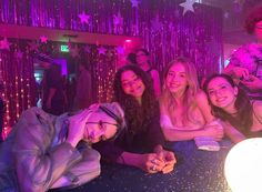 a group of people sitting at a table in a room with purple lights and streamers