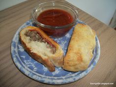 a blue plate topped with a sandwich next to a bowl of ketchup on top of a wooden table