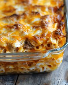 a casserole dish with meat and cheese in it sitting on a wooden table