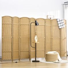 a room divider made out of woven material with a lamp next to it on the floor