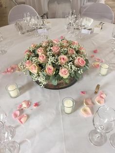 a centerpiece with pink roses and baby's breath sits on a white table cloth