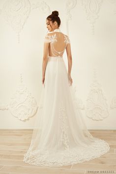 a woman in a white wedding dress standing on a wooden floor with her back to the camera