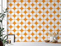 an orange and white geometric wallpaper in a room with a potted plant next to it