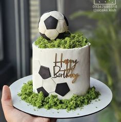 a soccer themed birthday cake with moss on the bottom and gold foil lettering that says happy birthday