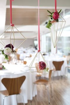 two hanging decorations with flowers on them in front of a table at a wedding reception