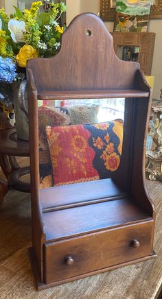 a wooden shelf with a mirror on top of it next to a vase and flowers