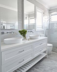 a white bathroom with two sinks and a large mirror