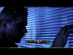 a man standing in front of a window with blue light coming through the blinds on his face