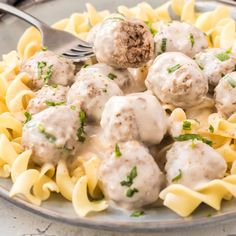 a plate full of meatballs and noodles with a fork