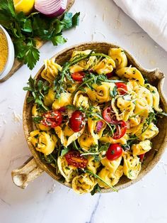 a bowl filled with pasta and vegetables on top of a white table next to other ingredients