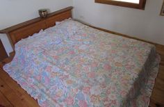 a bed with a flowered bedspread in a bedroom next to a window