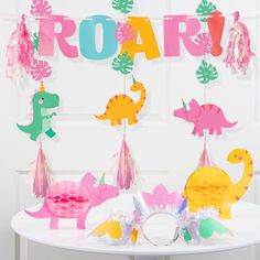 dinosaur party decorations on a table in front of a door with the word roar spelled out