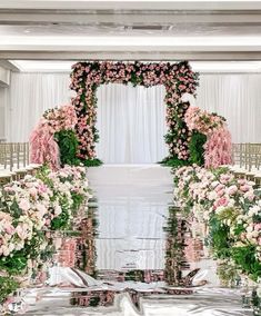 an aisle decorated with pink flowers and greenery