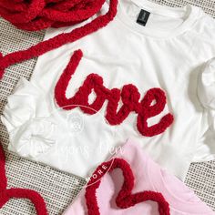 two t - shirts with the word love written on them and crocheted hearts