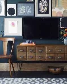 a living room with pictures on the wall and a television mounted to the wall above it