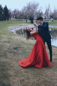 a man and woman dancing in front of a pond