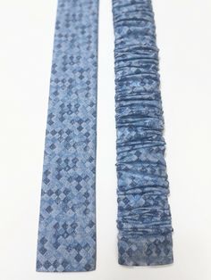 two ties that are laying side by side on a white surface, one is blue and the other is light blue