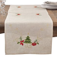 a christmas table runner with poinsettis and holly on it, along with silverware